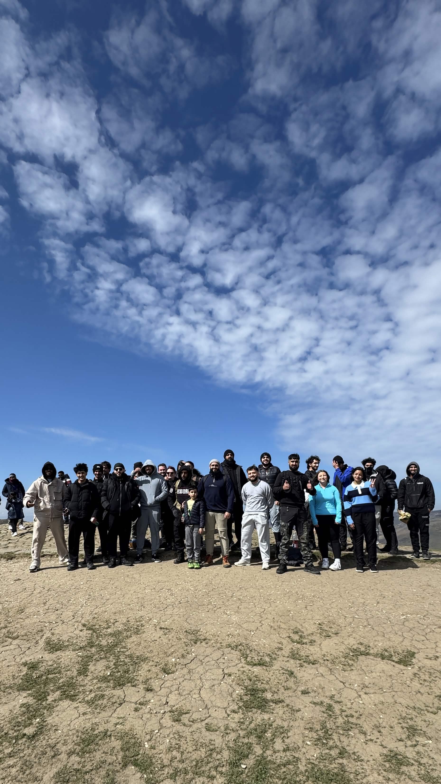 Large group standing on a clifftop under a cloudy sky