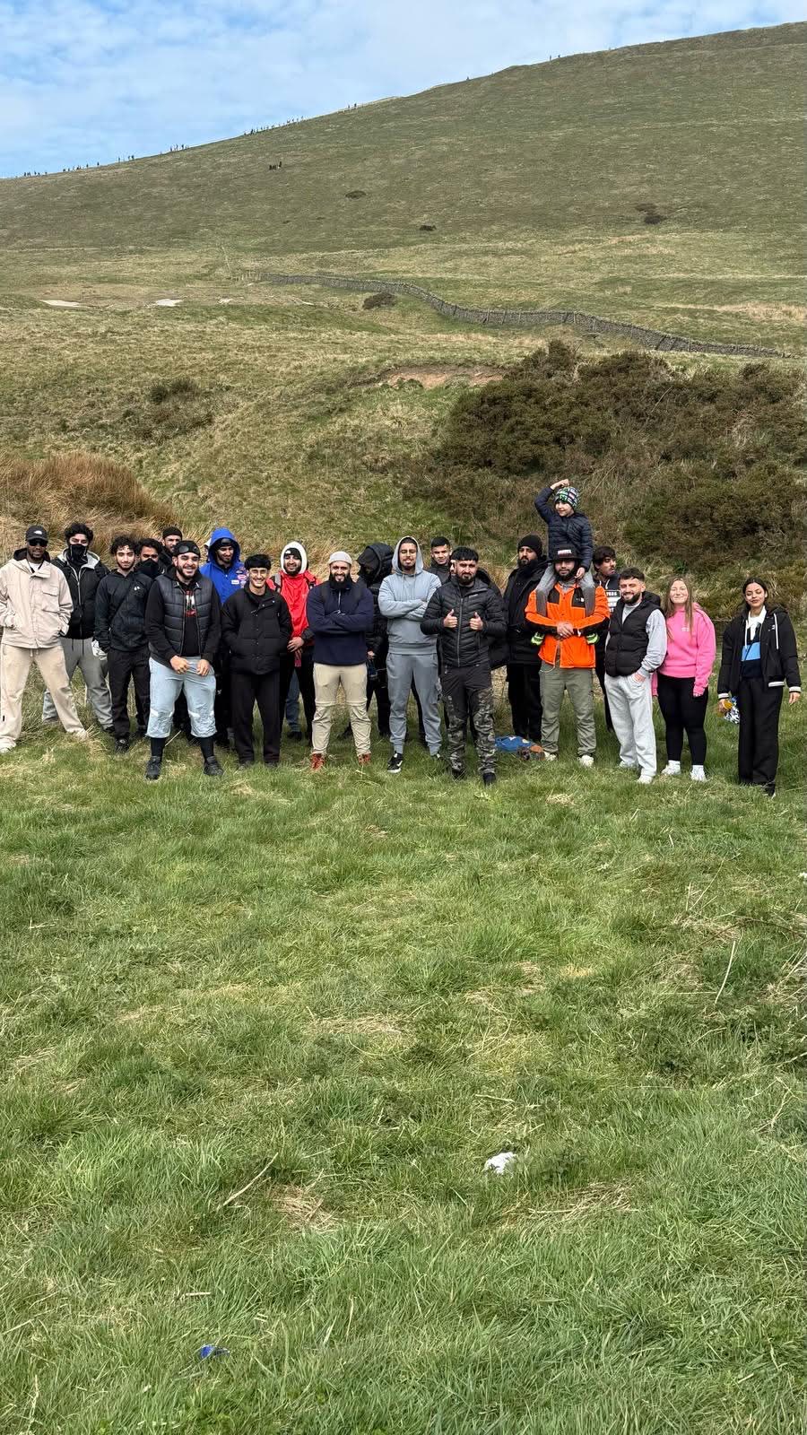 Large group sitting together on a sunny hilltop